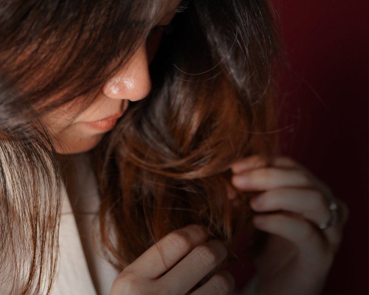 Woman looking down and running her hands through her hair