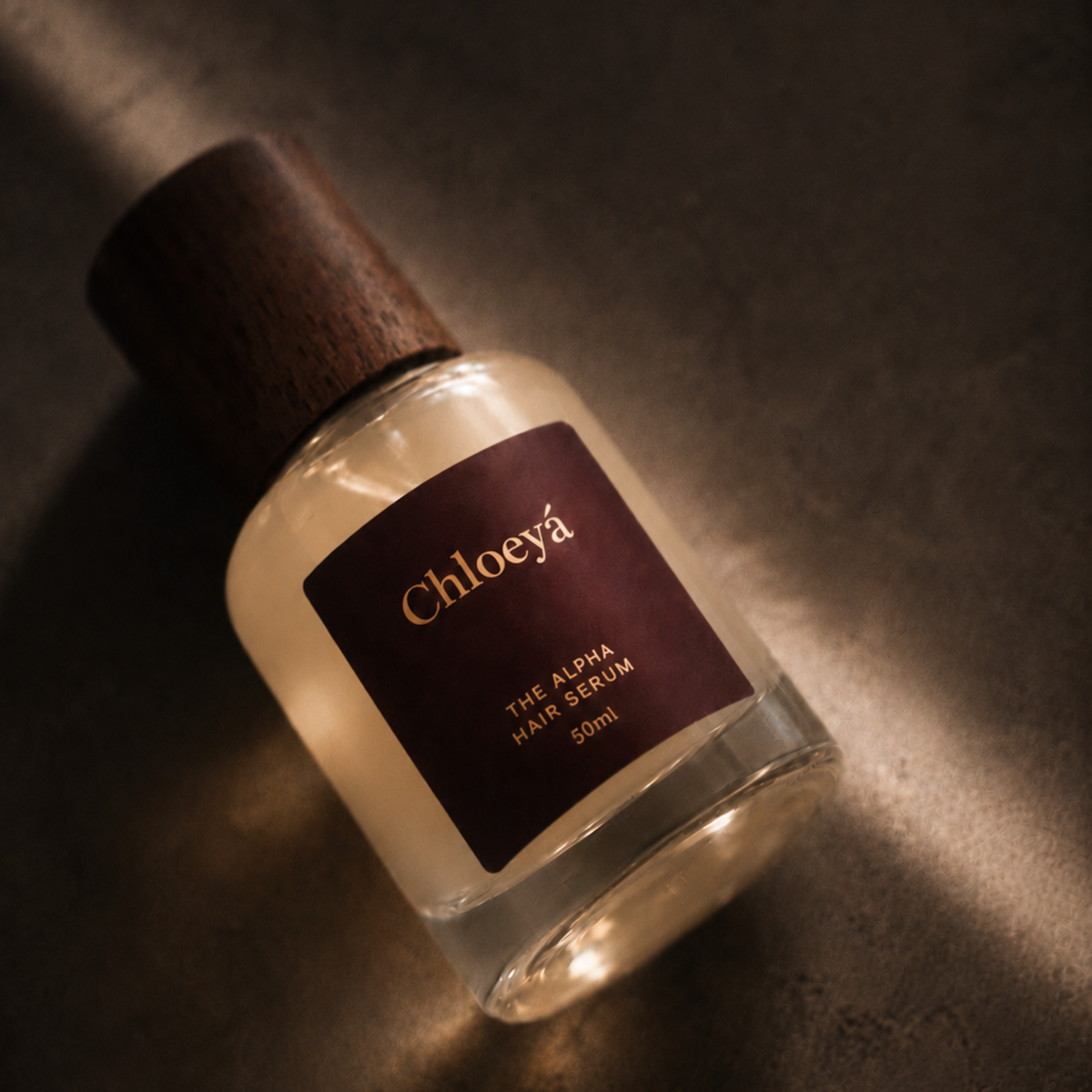 The Alpha Hair Serum bottle lying on its side on a warm textured surface, lit from one side